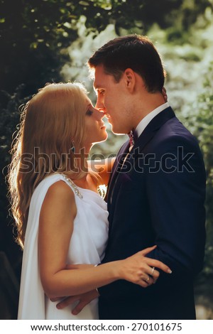 in love cute bride and groom look at each other in the midst of green leaves light falls Montenegro