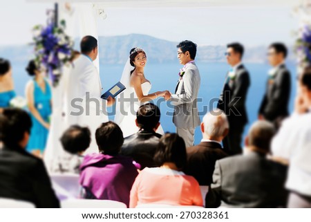 stylish rich smiling asian bride and groom  wedding ceremony hugging in island Santorini greece sunshine