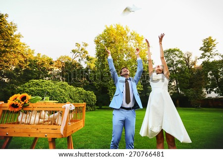 Happy smiling bride and groom hands releasing white doves on a sunny day