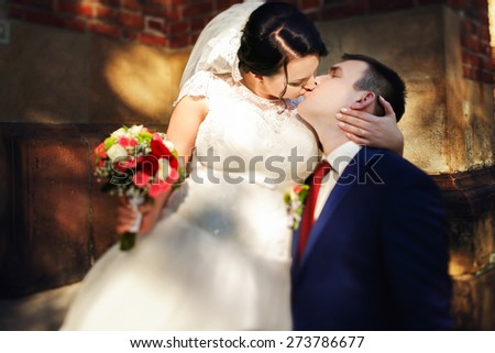 bride and groom walking kissing near trees and church