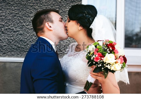 groom kisses the bride in a dress in a blue suit