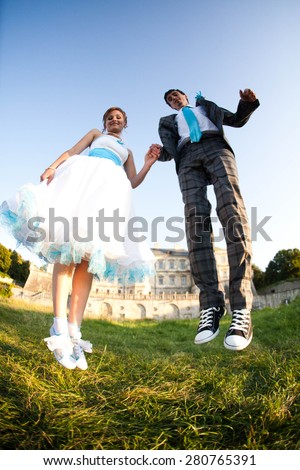 smiling couple is jumping on background green grass  and old castle