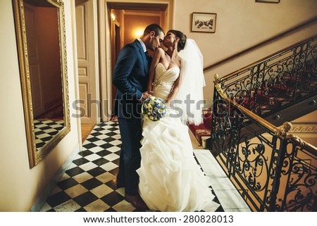 groom is kissing bride shoulder on the  background corridor with mirror