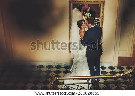groom and bride is hugging and kissing on the background miror