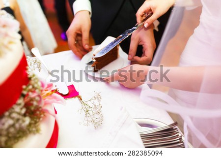 couple is cutting amazing tasty cake decorated with pink lilies and ribbons
