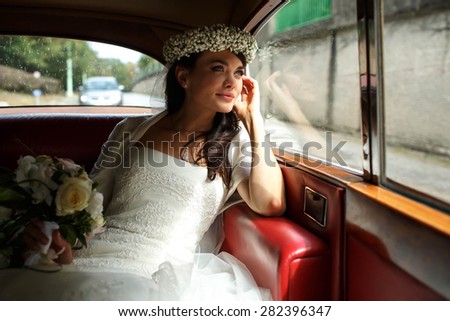 beautiful stylish luxury  bride in crown holding bouquet of orchids  and sutting in car