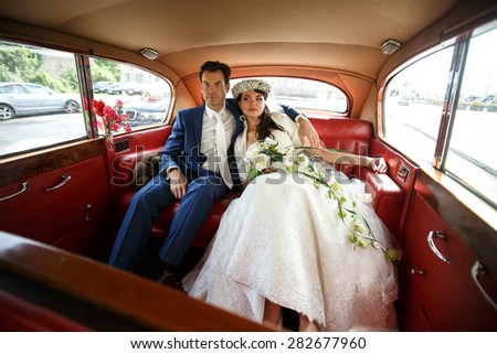stylish rich groom and bride on the background red car salon