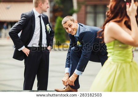 funny groom is cheking his shoes on the background city