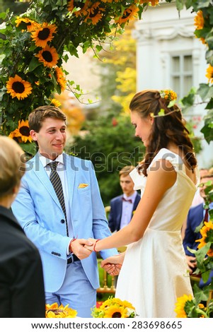 rich stylish groom and bride  holding hand near the arch of sunflowers wedding ceremony