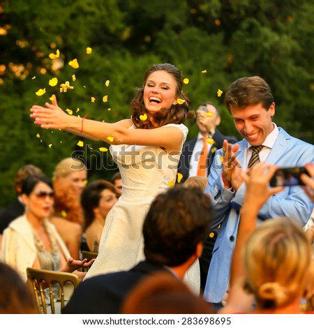 throw guests the petals on rich stylish groom and bride at wedding ceremony