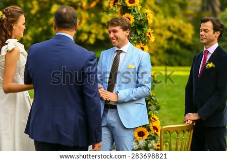 rich stylish groom and bride  with bestman near the arch of sunflowers