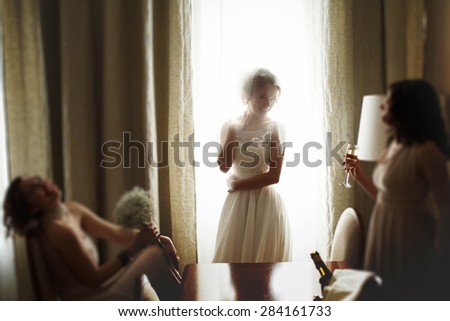 happy stylish gorgeous blonde bride with bridesmaids on the background  hotel room