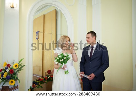 elegant blonde bride drinking champagne and elegant groom looking at her with love