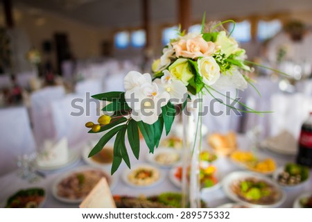 stunning unusual beautiful bouquet with orchids and roses in vase on the background of restaurant