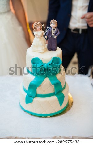 happy elegant married couple cuting beautiful cake in a restaurant, celebrating wedding