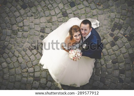beautiful happy stylish bride with elegant groom  on paving road the background of  old city
