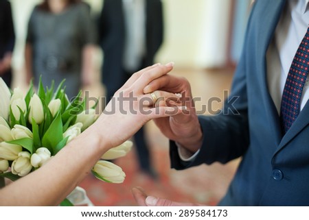 elegance groom putting on wedding ring on fingers lovely bride