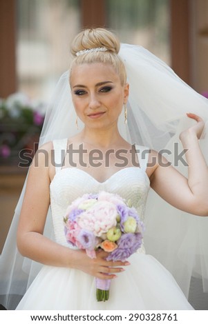 unusual beautiful bouquet of peonies is holding stylish gorgeous blonde bride