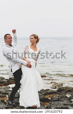 beautiful  gorgeous blonde bride  and stylish groom having fun, on the background of a sea, wedding ceremony  on cyprus
