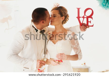 beautiful  gorgeous blonde bride  and stylish groom with red letters love, hawai  colorful sand ceremony  on cyprus