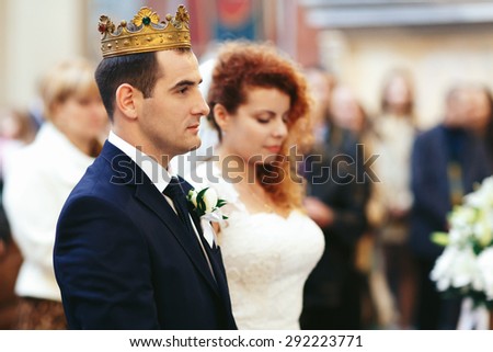stylish luxury red haired bride and elegant groom, with crowns, wedding ceremony in the old church