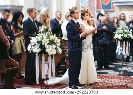 stylish luxury red haired bride and elegant groom, with crowns and candles, wedding ceremony in the old church