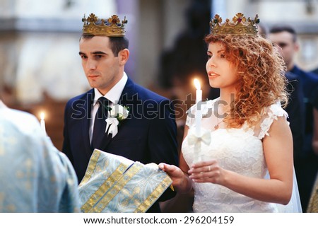 stylish luxury red haired bride and elegant groom, with crowns and candles, wedding ceremony in the old church