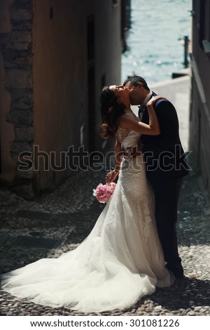 sweet romantic beautiful happy couple kissing at stone streets of the ancient city, mediterranean sea, mountains
