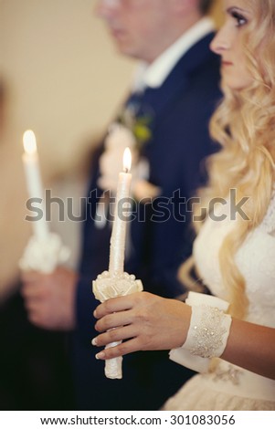 wedding ceremony of stylish elegant blonde bride and groom with holding candles in the old church