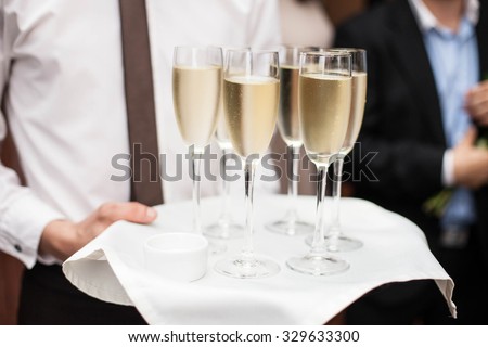 Restaurant waiter brings people and alcohol champagne on a tray