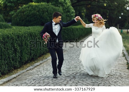 Happy wedding couple charming groom and blonde bride dancing in park