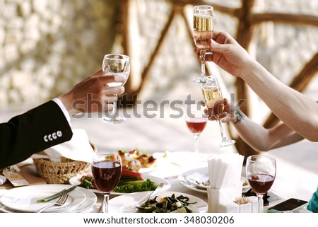 Hands of people with glasses of champagne or wine, celebrating and toasting in honor of the wedding or other celebration.