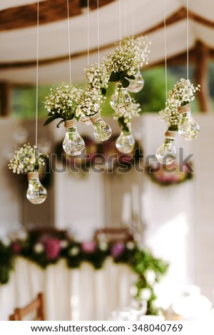 Luxury original wedding floral decoration in the form of mini-vases and bouquets of flowers hanging from the ceiling.