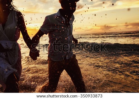 beautiful sunset in the ocean and happy couple running together