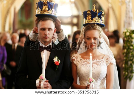 Wedding in the church, bride and groom under crowns