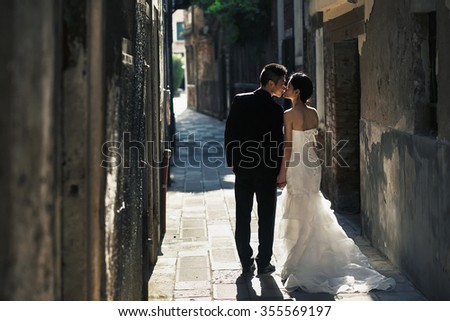 Young beautiful Asian bride and groom on the wedding  walk through the streets of old Venice, Italy.