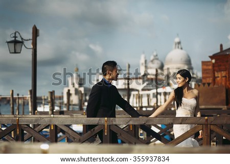 Young beautiful Asian bride and groom on the wedding  walk through the streets of old Venice, Italy.