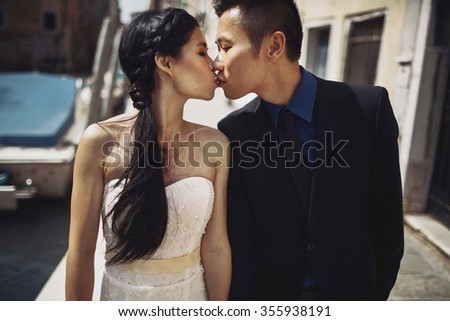 Beautiful stylish Asians bride and groom walking on the summer streets of Venice, Italy