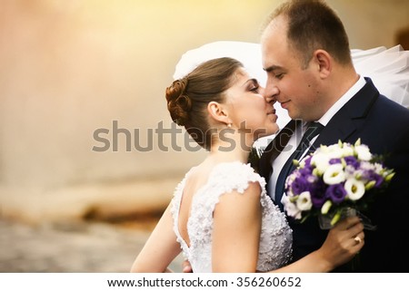 Beautiful smiling happy young couple kissing  on the street on their wedding day, close up portrait