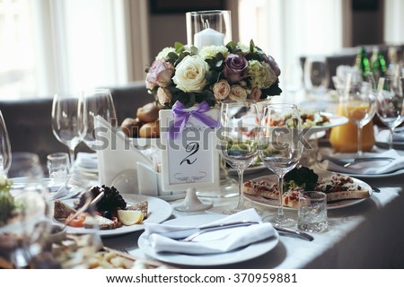 Elegant table arrangement and catering at wedding reception, stylish bouquet centerpiece