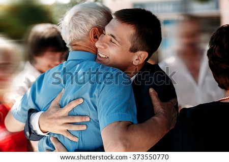 Groom on his wedding day hugging relatives outdoors