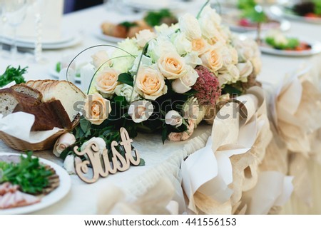 Wooden lettering lies behind a bouquet of beig roses on the dinner table