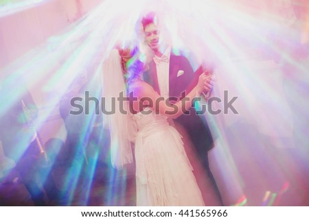 Bride and groom look like the angels dancing in the bright rays of disco lights