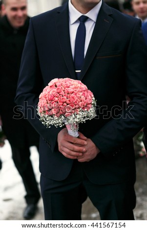 The groom keeps bouquet for bride