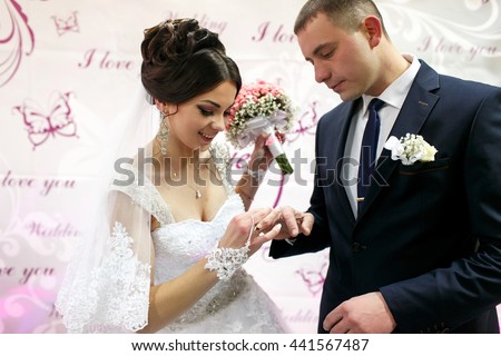 The brides wear rings near wedding banner