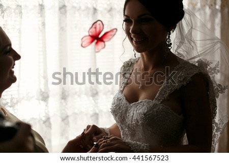The bridesmaid and bride hold hands in the room