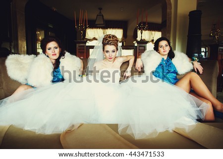A look from afar on bride and bridesmaids sitting on the couch in provoking manner
