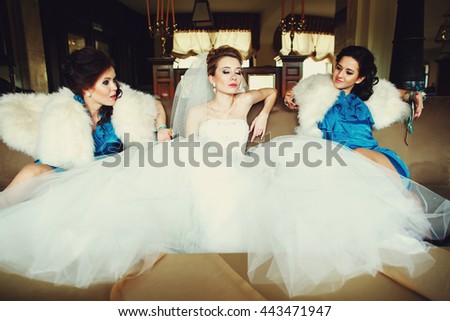 Bride and bridesmaids look cool posing on the big beig couch
