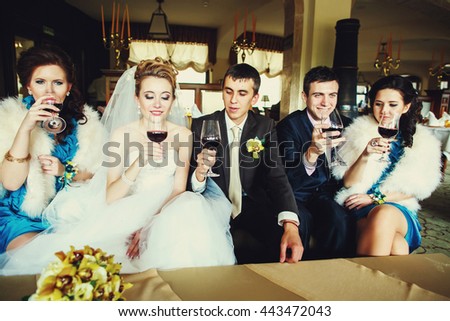 Newlyweds and friends drink wine sitting on the couch