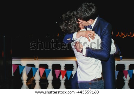 Groom kisses his friend standing on the  shore at night